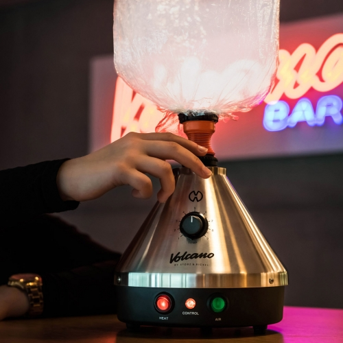 Volcano Classic Vaporizer mit Ballon in Lounge umgebung, im Hintgergrund mit Valcano Bar Neonlichreklame